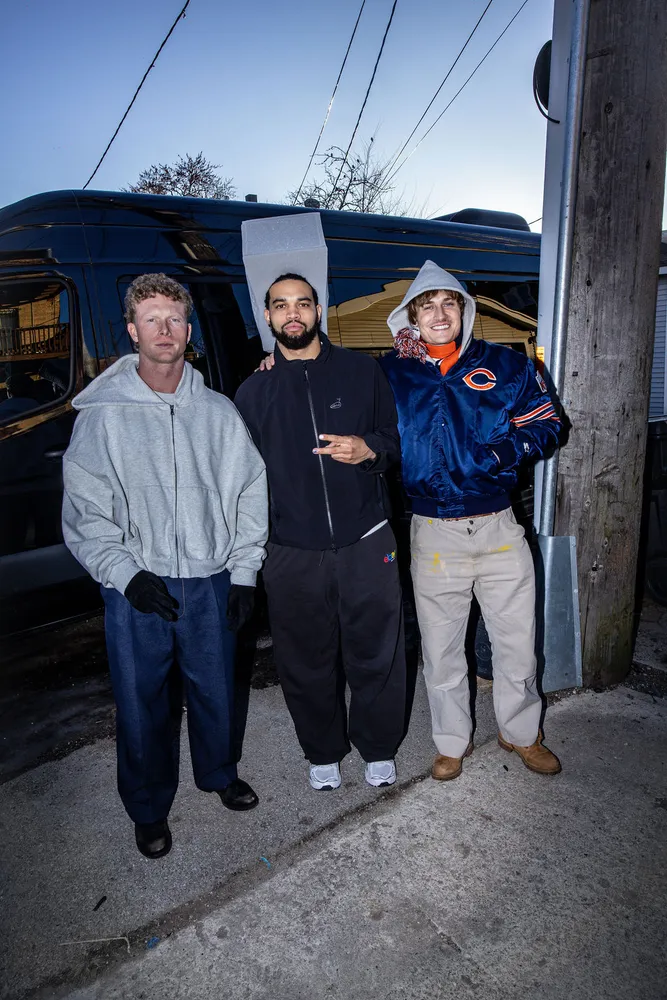 Three people posing together outside a storefront