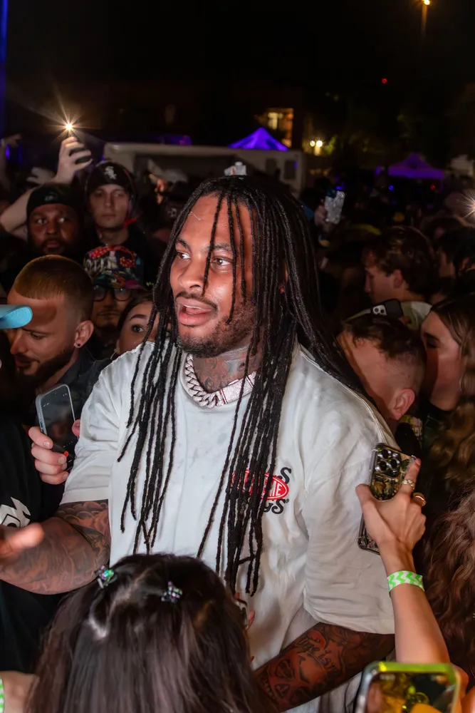 Performer with long braids surrounded by fans at a concert