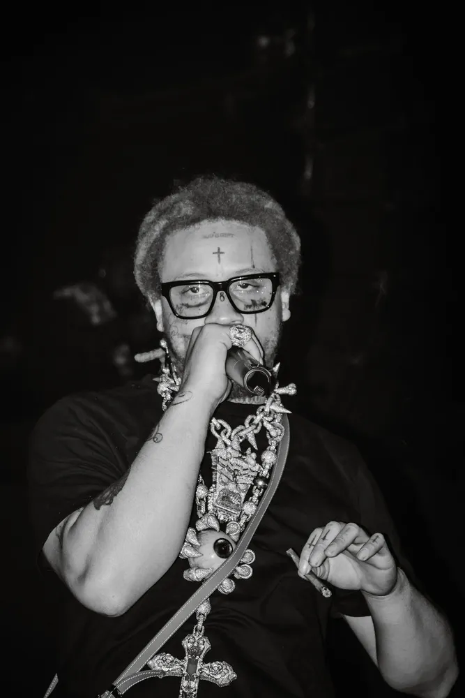 Black-and-white concert portrait of a performer wearing glasses