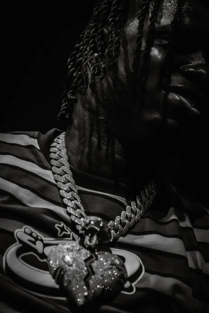 Dark black-and-white close-up of a performer and pendant