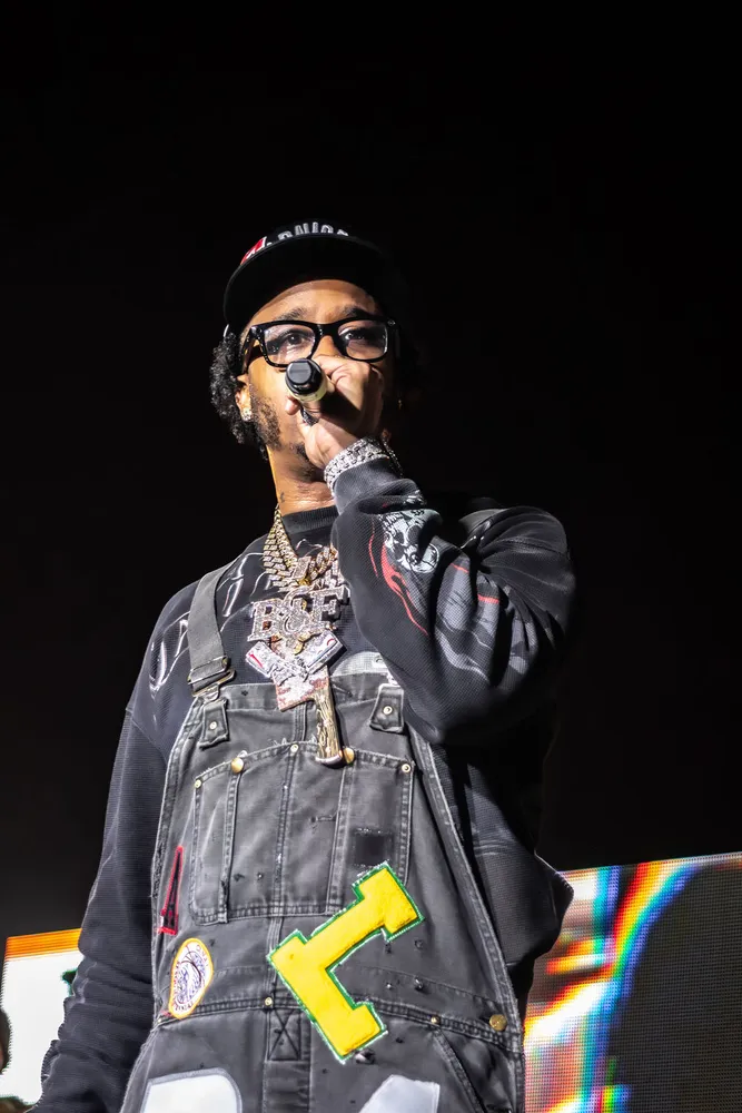Performer in sunglasses singing into a microphone on stage