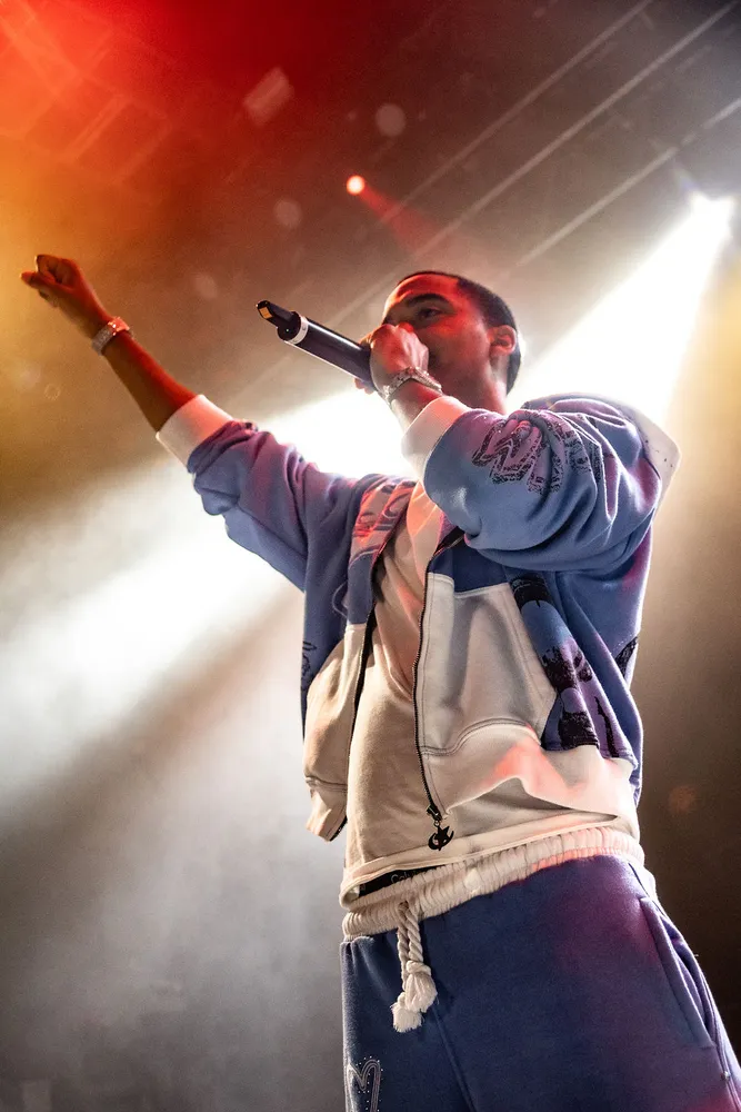 Performer raising an arm beneath red and white stage lighting