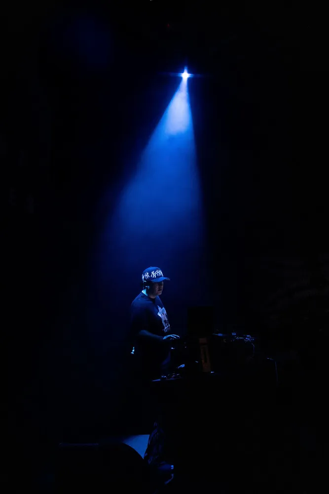 Performer standing beneath a single blue spotlight