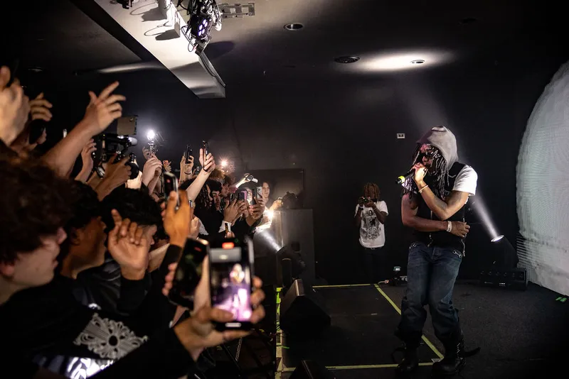 Performer facing raised hands in an intimate concert venue