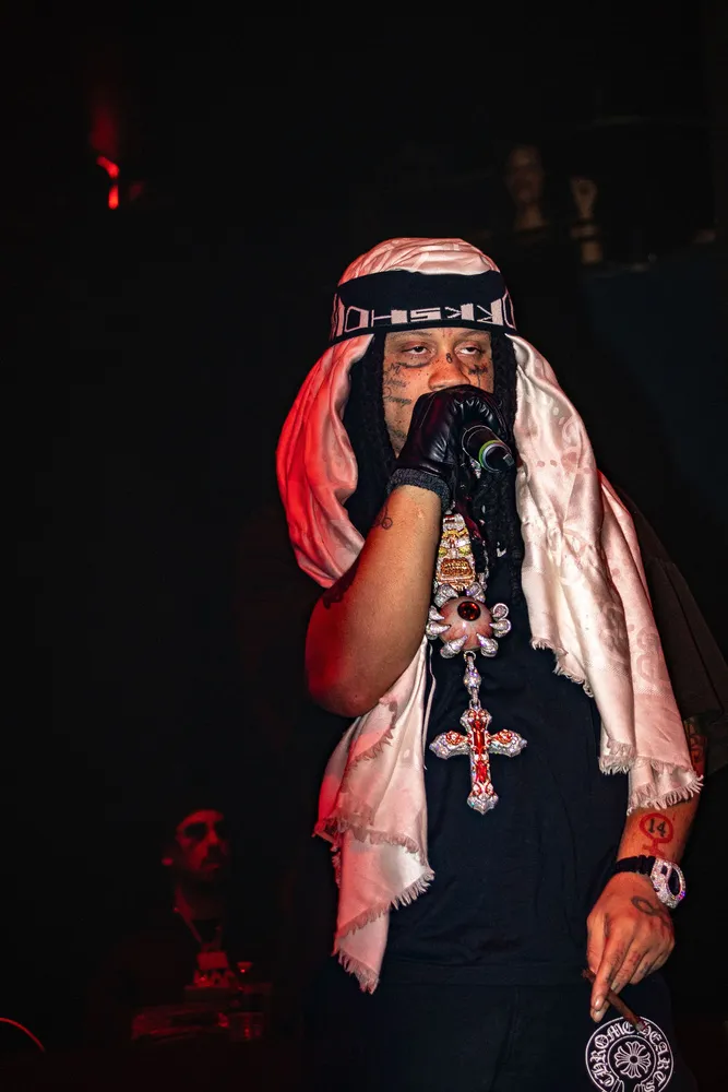 Performer with a head covering singing against a dark stage