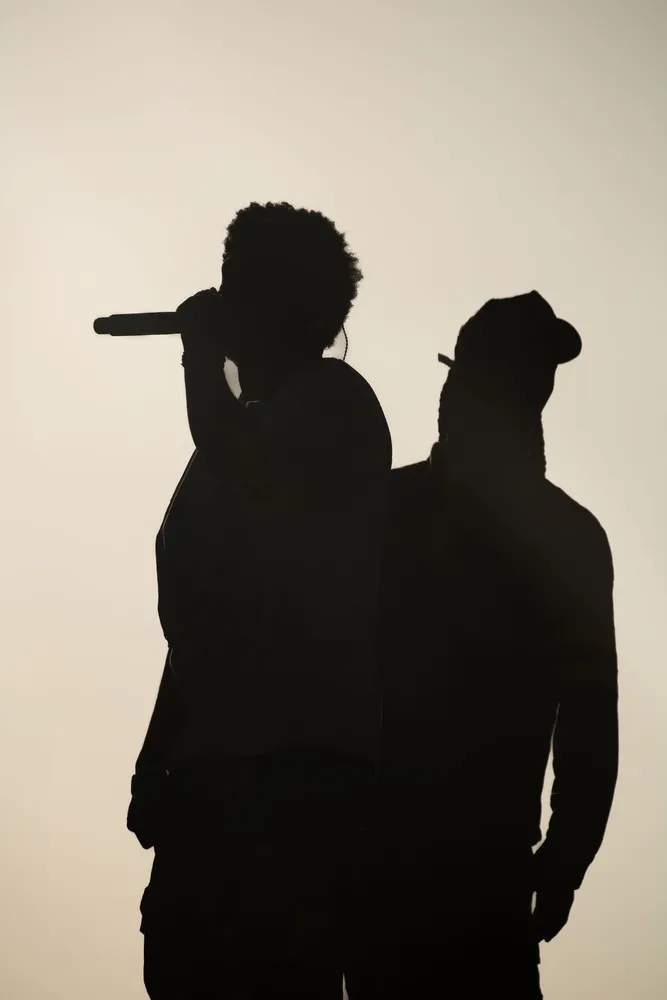 Two performers silhouetted against a warm stage backdrop