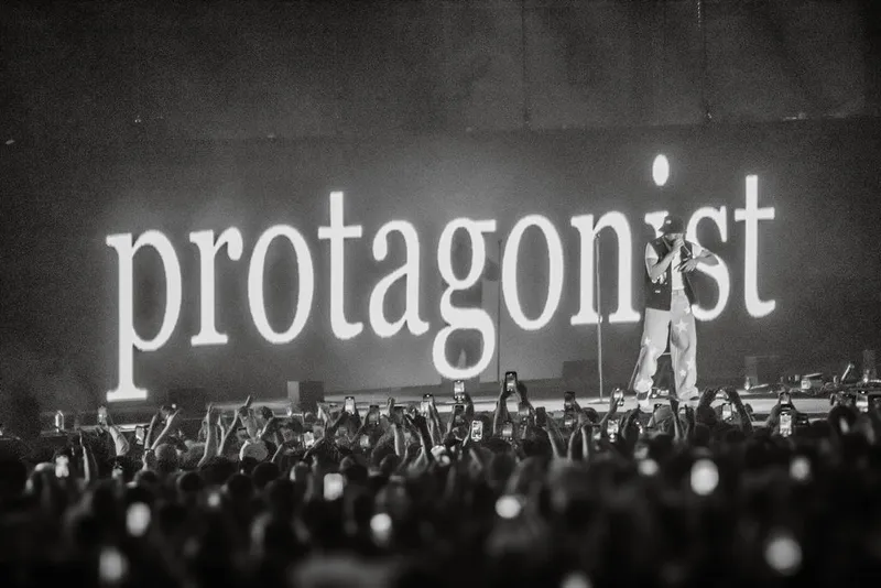 Black-and-white crowd beneath the Protagonist stage screen