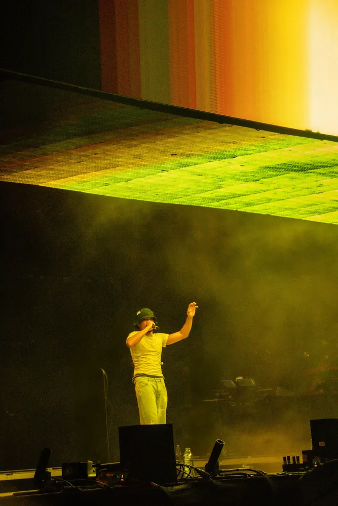 Performer standing beneath a vivid yellow stage light