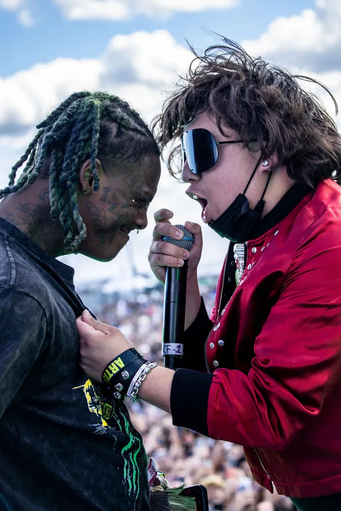 Two performers sharing a microphone at an outdoor festival
