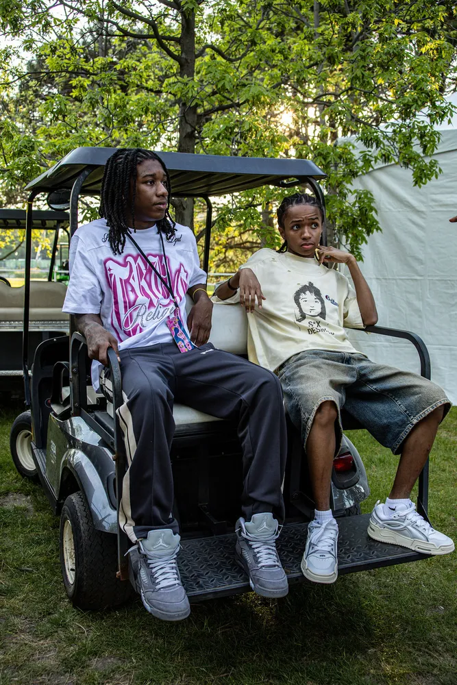 Two people riding a golf cart backstage at an outdoor festival