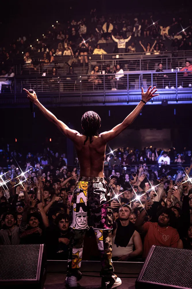 Performer raising both arms toward a packed audience