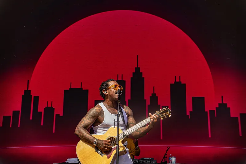 Guitarist in front of a red circle and city skyline backdrop